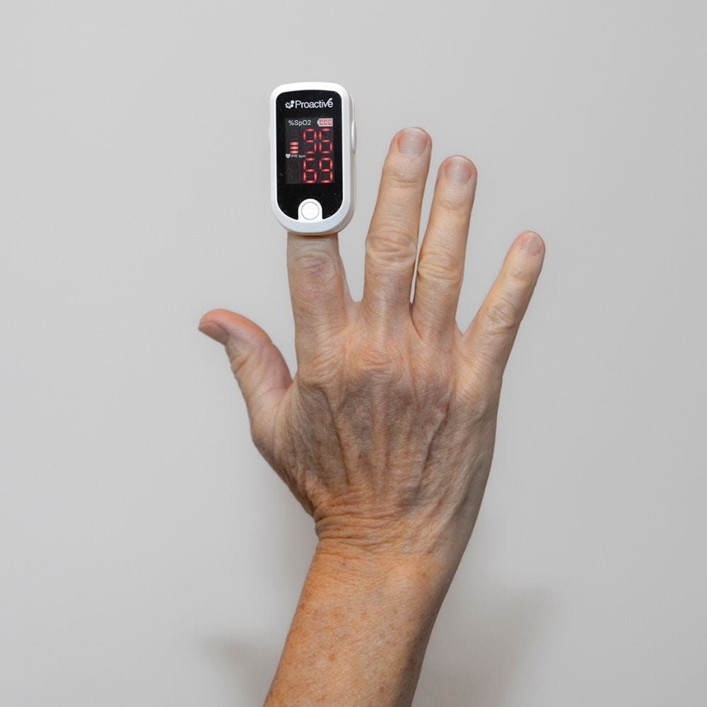 Finger with a pulse oximeter on a plain background