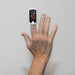 Finger with a pulse oximeter on a plain background