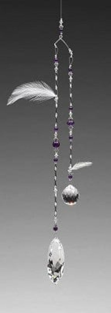 Decorative hanging mobile with crystals, feathers, and beads on a gray background
