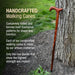 Handcrafted walking cane leaning against a tree with promotional text about its traditional craftsmanship.