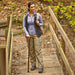 Woman with a walking stick standing on a wooden bridge in a forest