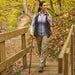 Woman hiking on a wooden bridge in a forest during autumn