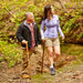 Man and woman walking along a forest path with canes.