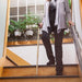 Person using a cane to ascend a set of stairs indoors.