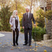 Man and woman walking together on a path with autumn leaves, holding canes.