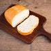 Loaf of bread sliced on a wooden cutting board with a rustic wooden background