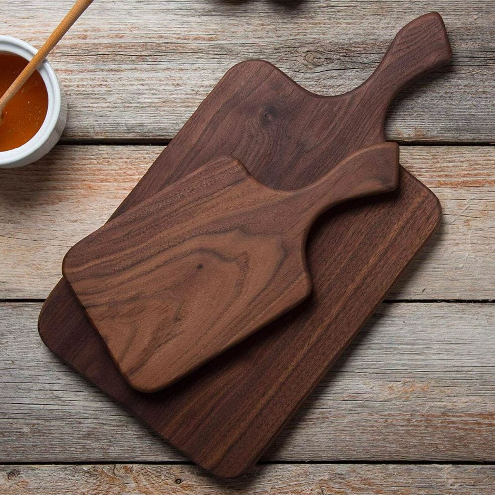 Two wooden cutting boards on a rustic wooden surface with a small bowl of sauce.