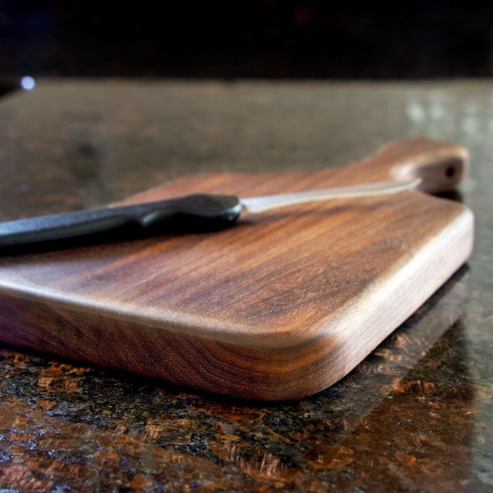 Wooden cutting board with a knife on a dark surface