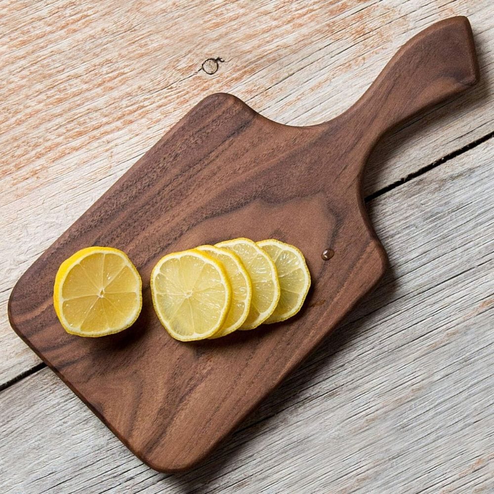 Sliced lemons on a wooden cutting board with a rustic wooden surface.