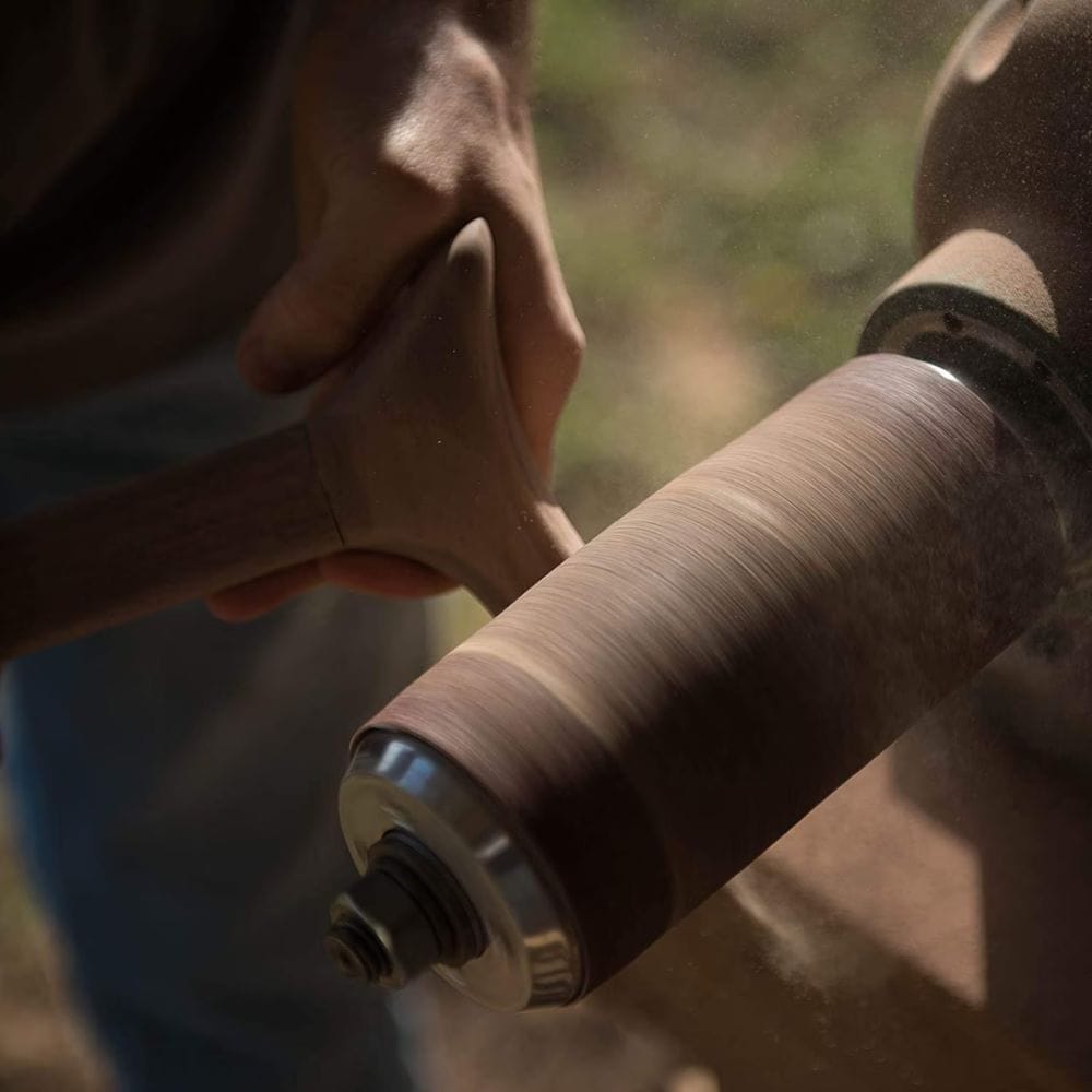 Close-up of a person holding a fishing reel with a blurred natural background