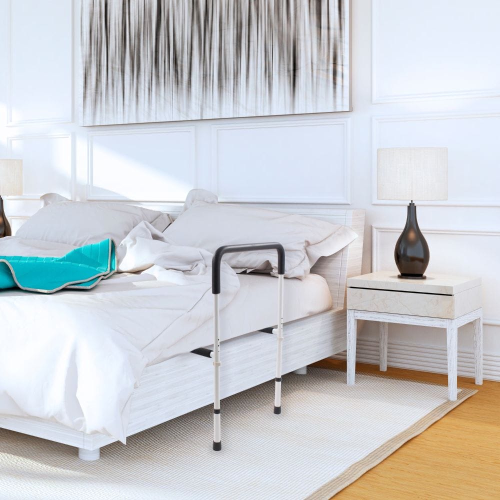 Bed with a bed rail in a bedroom setting with a nightstand and lamp.