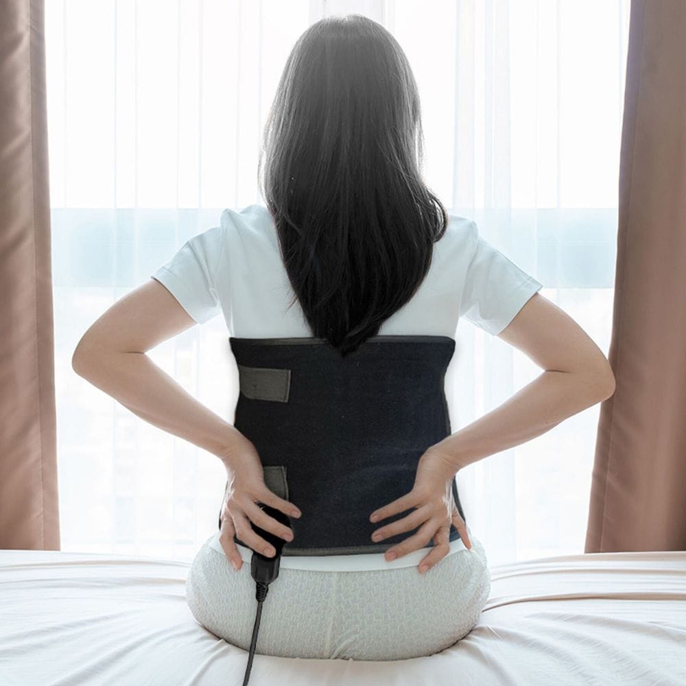 Person using a back massager on a bed with a neutral background