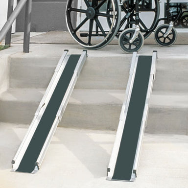 Two wheelchair ramps on a set of stairs with a wheelchair in the background.