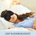 Person wearing a black sleep mask while lying in bed, with text 'LIGHT BLOCKING/BLACKOUT' at the bottom.