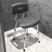 Gray shower chair with backrest on a tiled floor