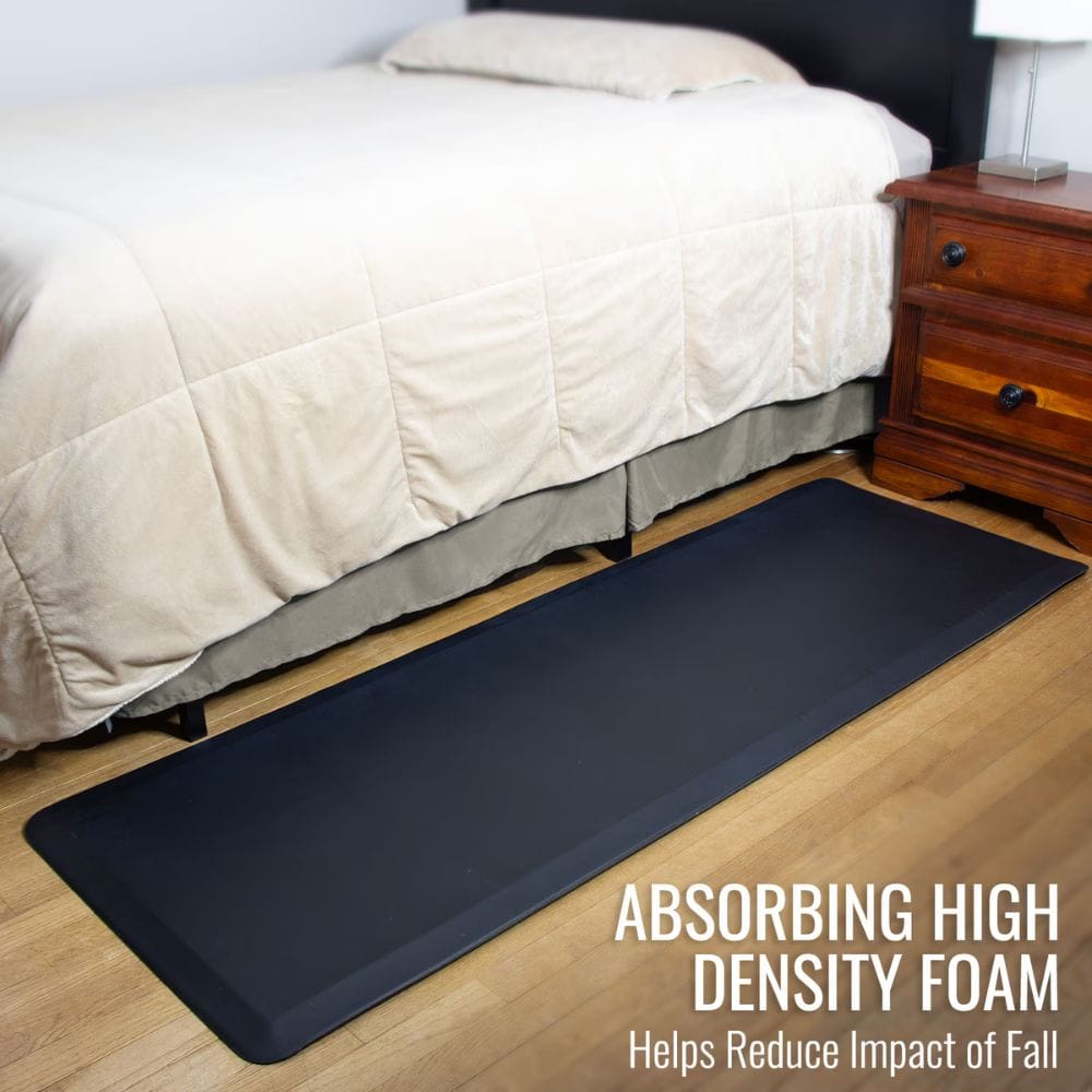 Black anti-fatigue mat in front of a bed with text highlighting its benefits.