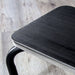 Close-up of a black metal footstool on a light wood floor.