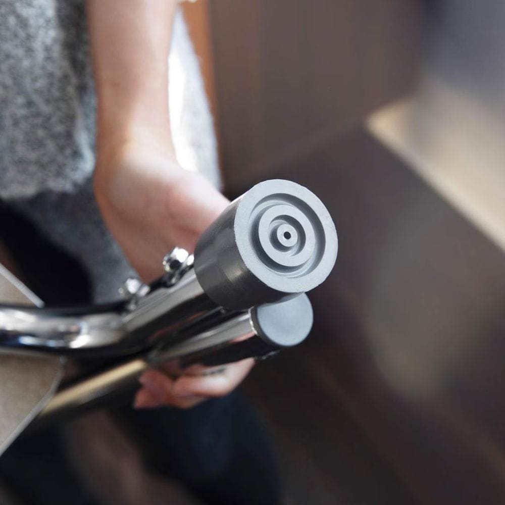 Close-up of a metallic handlebar with a person's hand holding it, blurred background