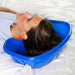 Woman lying on a white blanket with a blue basin over her head