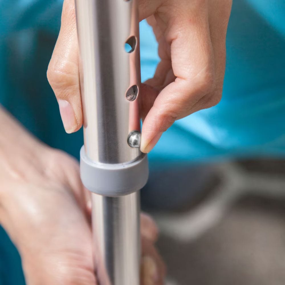 Person adjusting a metal rod with screws against a blurred background