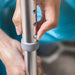 Person adjusting a metal rod with screws against a blurred background