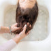 Person washing hair in a sink with hands gently holding the hair.