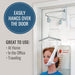 A white and silver over-the-door weight bag hanging from a metal door-hanging system mounted on a white door, with a woman visible below the bag. Text on the left reads 'EASILY HANGS OVER THE DOOR' and 'GREAT TO USE: At Home, In the Office, Traveling'.