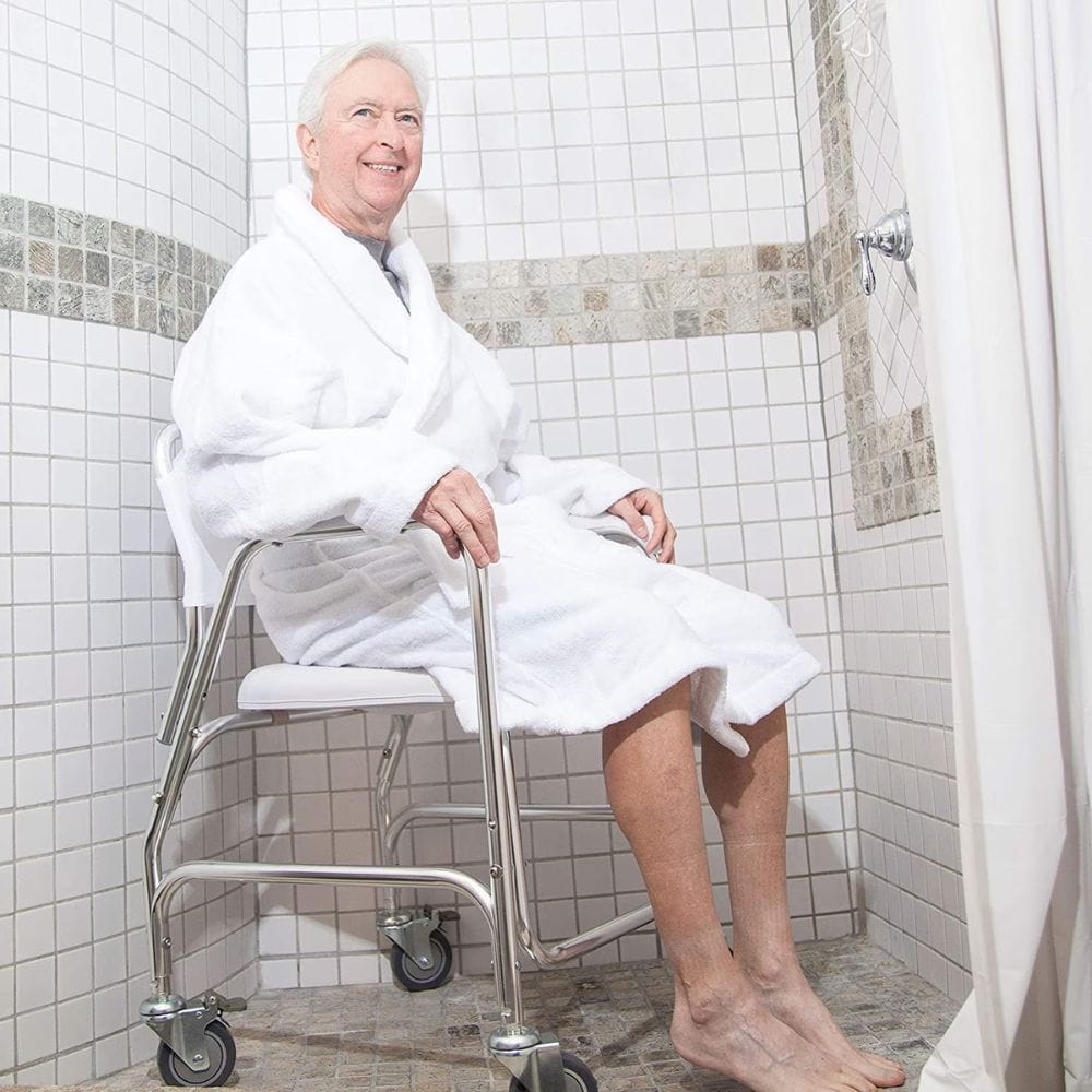 Man in a white robe sitting on a shower stool in a tiled bathroom.