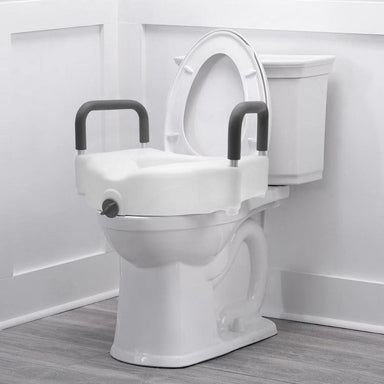 White toilet with a raised seat and handles in a bathroom setting
