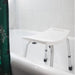White adjustable bath seat with gray legs in a bathroom setting.
