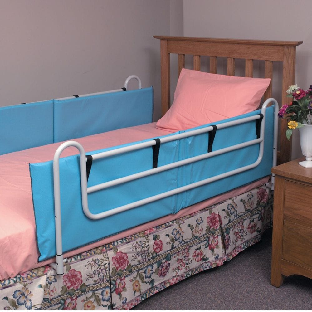 Bed with a blue safety rail and pink bedding in a bedroom setting.