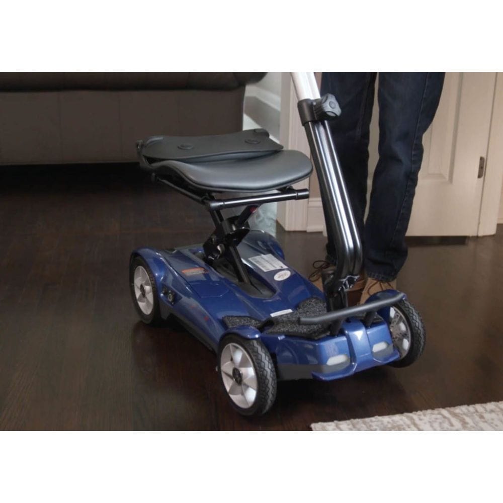 Blue mobility scooter with a person's leg wearing jeans and brown shoes on a wooden floor.