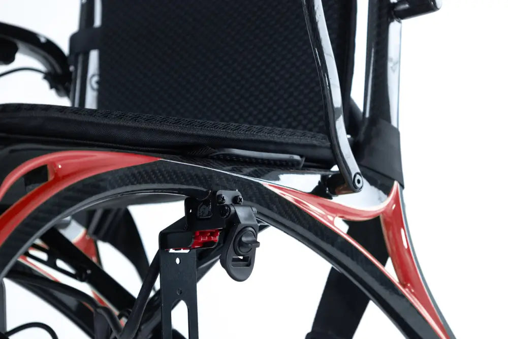 Close-up of the Monarch Mobility Ezi-Fold Carbon’s lightweight carbon fiber frame with orange accents beneath the seat.