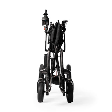 A black power wheelchair shown from the rear three-quarter view, folded and standing upright on a clean white studio background.