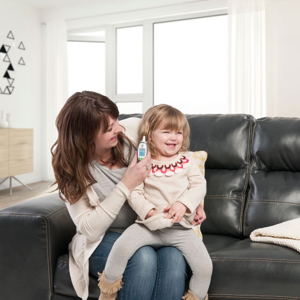 Woman holding a child on a couch in a bright living room