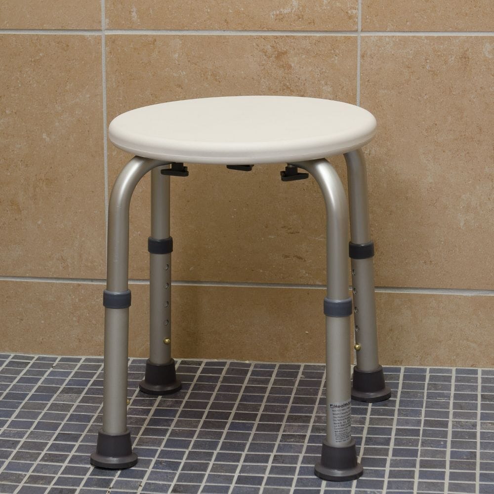 Round shower stool with metal legs on a tiled bathroom floor.