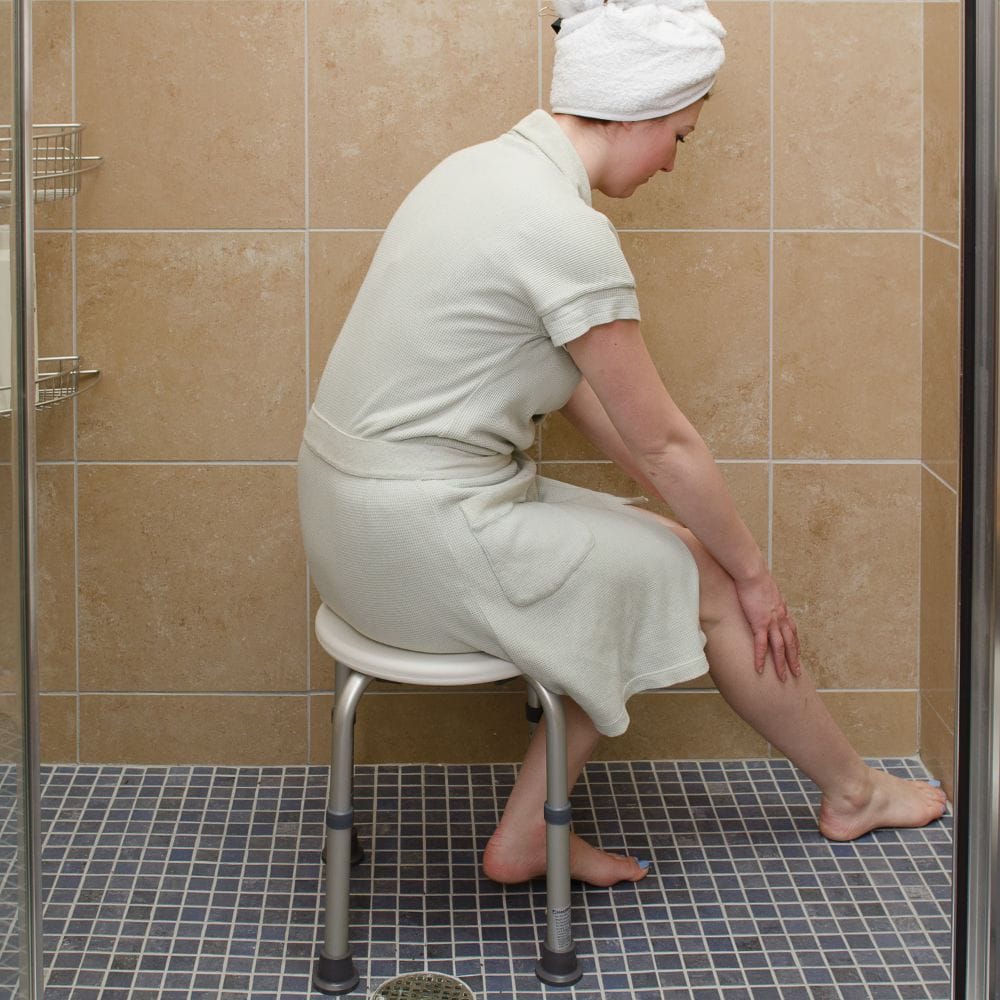 Person sitting on a stool in a tiled bathroom