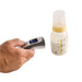 Hand holding a digital thermometer next to a baby bottle on a white background