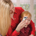 Woman using a digital thermometer on a child's forehead indoors.