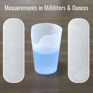 Three measuring cups with liquid, showing measurements in milliliters and ounces on a wooden surface.
