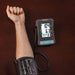 Digital blood pressure monitor on a person's arm with a brown background