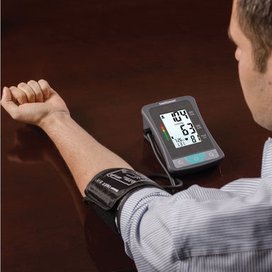 Person using a blood pressure monitor on their wrist with a dark background