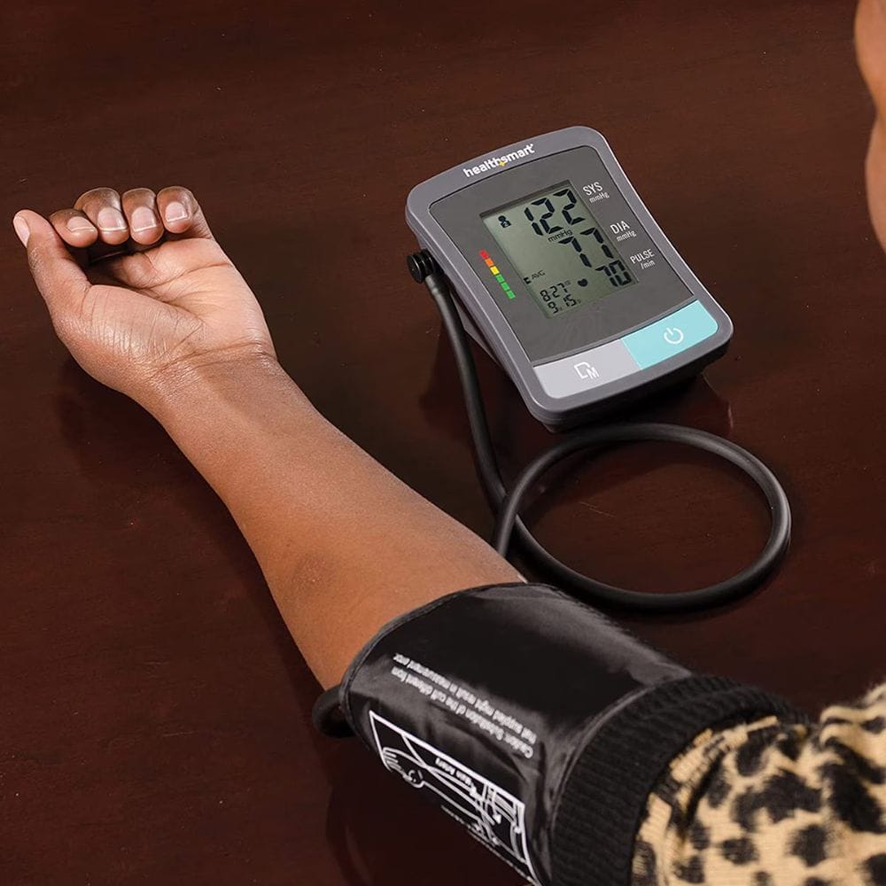 Digital blood pressure monitor on a person's arm with a brown background