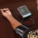 Digital blood pressure monitor on a person's arm with a brown background
