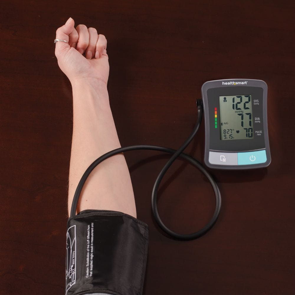 Person using a Healthnet blood pressure monitor on a wooden surface