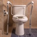 Beige toilet with metal safety rails in a tiled bathroom
