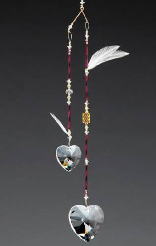 Decorative hanging ornament with heart-shaped crystals and feathers on a dark background