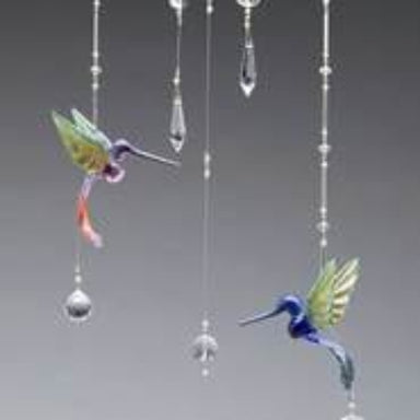 Decorative hummingbird wind chimes with hanging crystals on a gray background