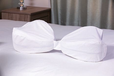 Two white Legacy Pillow Cases joined together on a bed to connect two leg pillows for full-leg support.