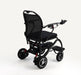 A black electric wheelchair with a mesh backrest, padded seat, and small front caster wheels, photographed on a clean white studio background.